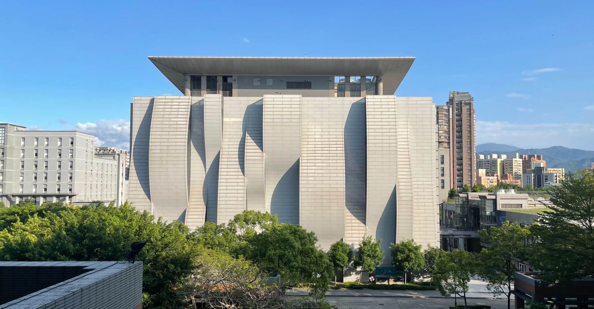 NTPU Library, the iconic building at National Taipei University. The Master Program in Smart Healthcare Management is located at the College of Social Science Building, the left side of the library. On a sunny day at about 3-5pm, there will be geometric shape of shadows on the wall. You can see the view through the window from the program office.